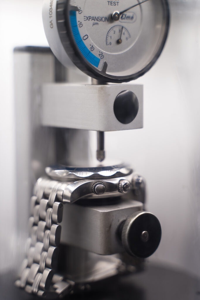 Omega watch undergoing pressure testing after a premium battery reseal, shown secured in a professional testing device.