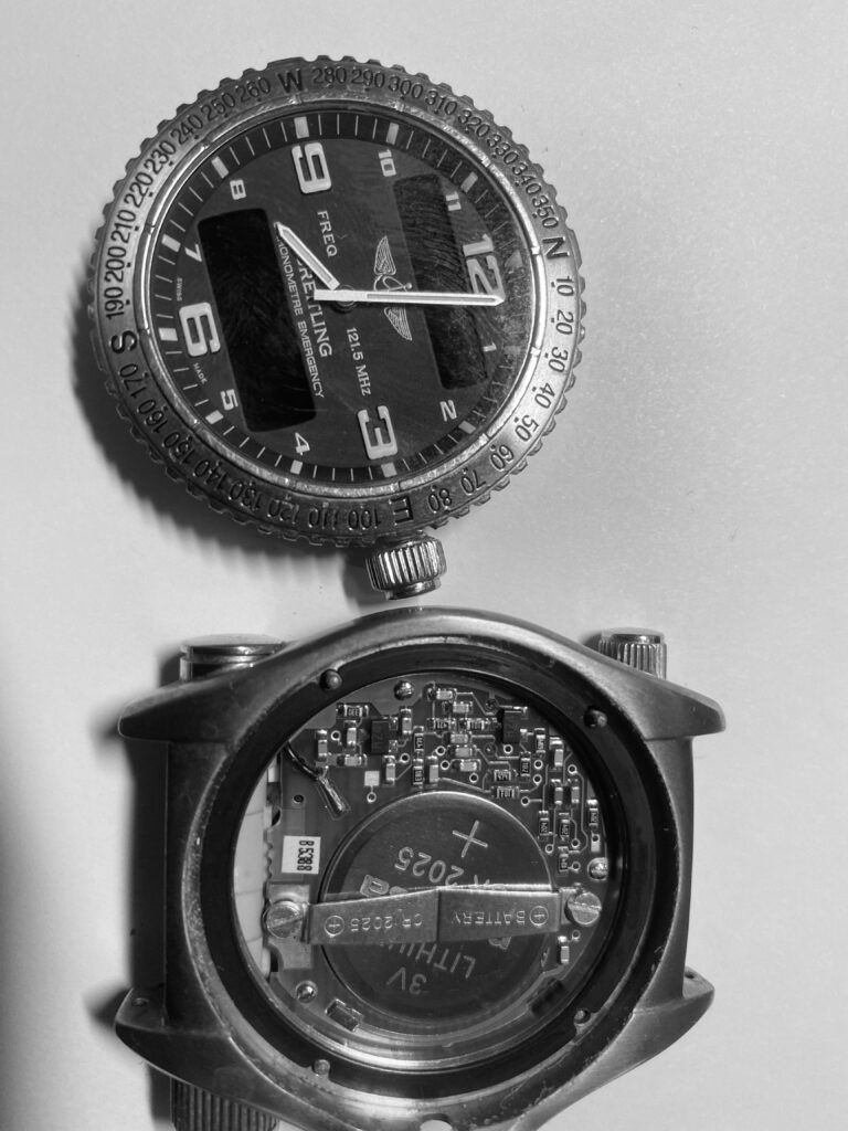 Close-up of a Breitling Emergency watch during a premium battery reseal service, showing the dial and exposed quartz movement.
