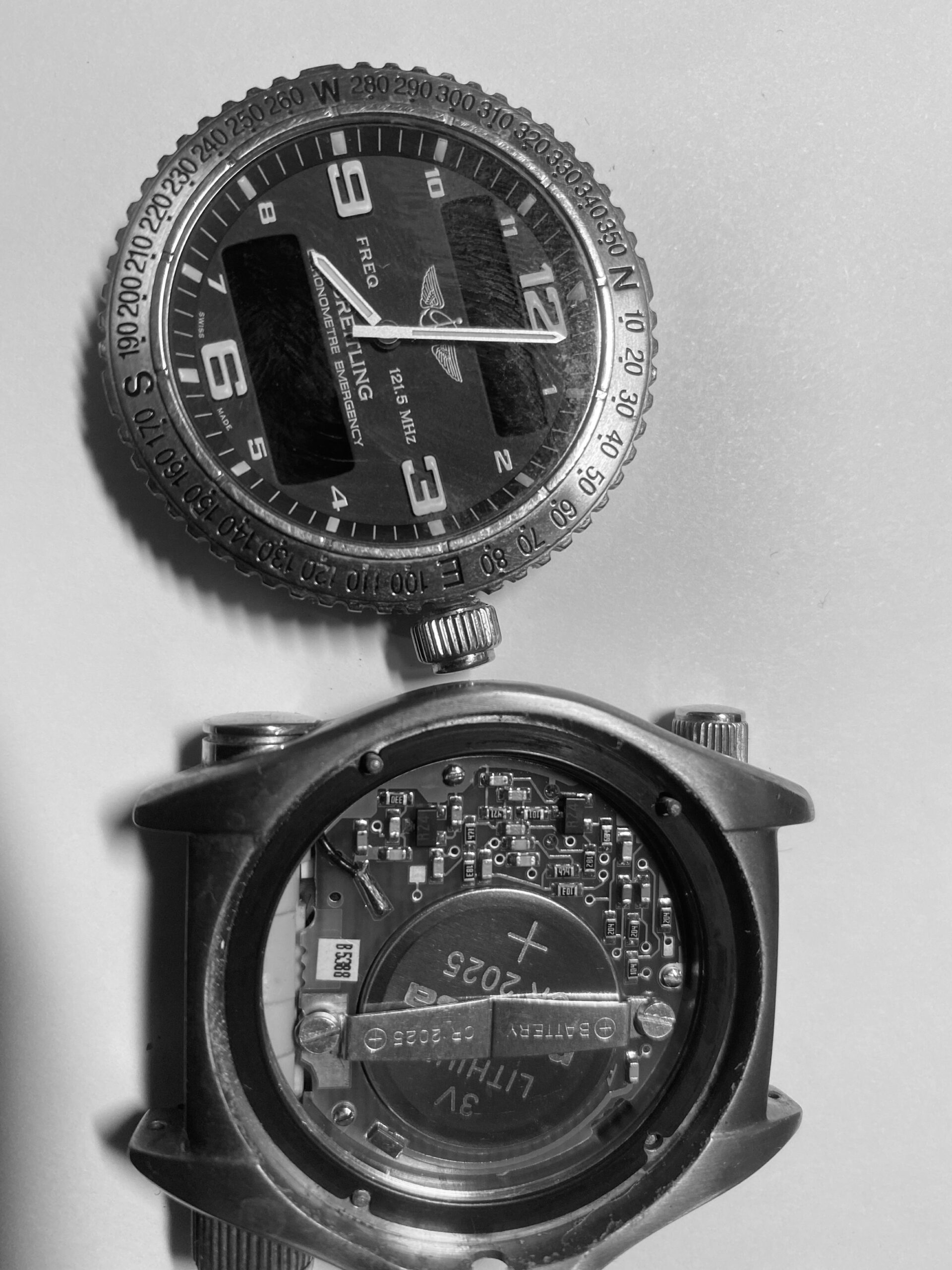 Close-up of a Breitling Emergency watch during a premium battery reseal service, showing the dial and exposed quartz movement.