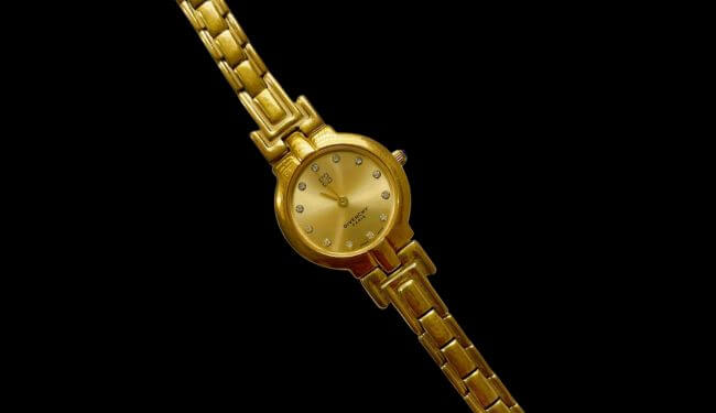 Gold-tone Givenchy watch on a matching bracelet photographed on a black background