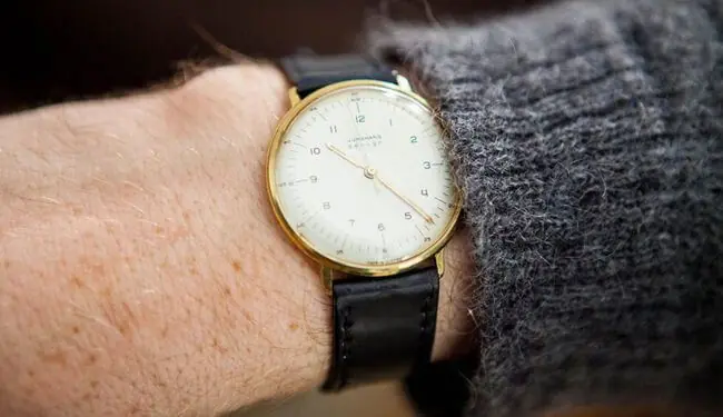 Junghans-style watch on wrist with white dial and black leather strap – junghans watch repair