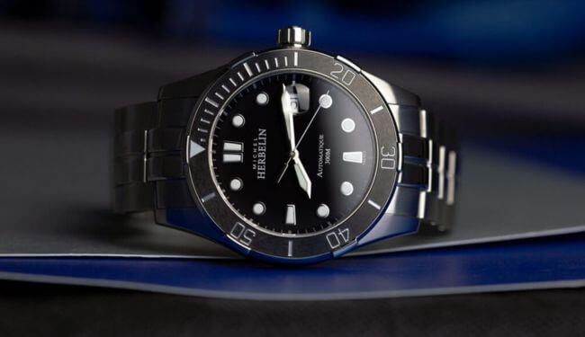 Michel Herbelin-style black dial watch on dark blue background – michel herbelin watch repairs