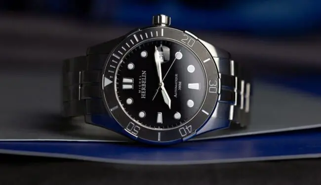 Michel Herbelin-style black dial watch on dark blue background – michel herbelin watch repairs