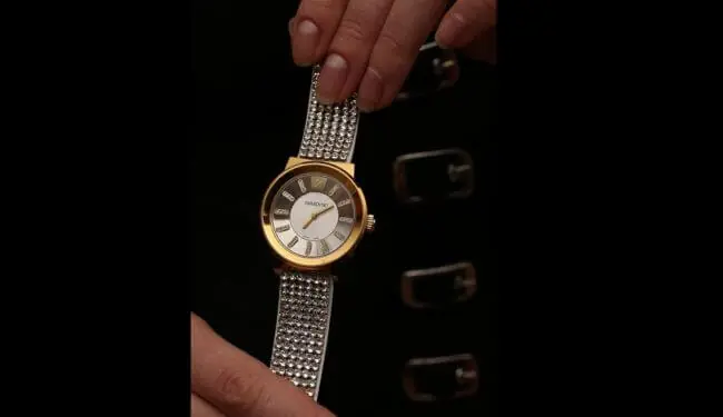 Swarovski watch repairs – gold-tone Swarovski watch with crystal bracelet held in hand