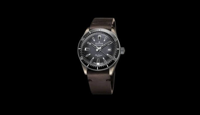 Edox watch with a dark dial on a brown leather strap against a black background
