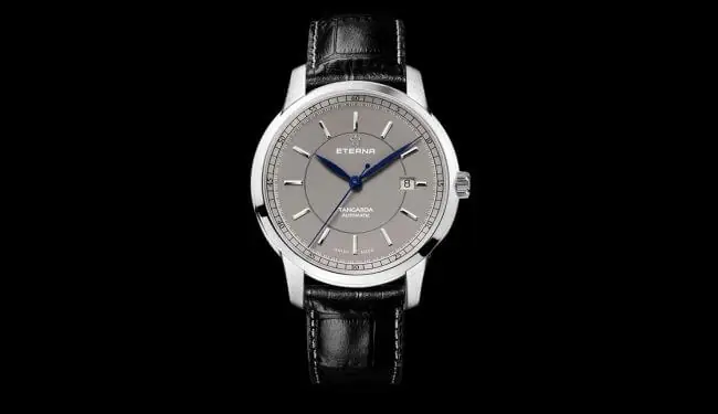 Eterna watch with a silver dial on a black leather strap against a black background