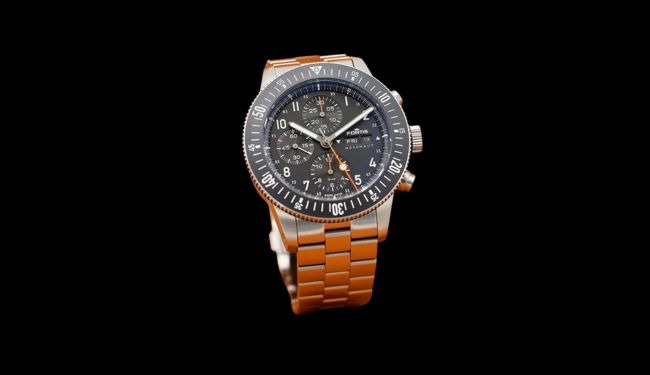 Fortis watch with a dark dial on an orange strap against a black background