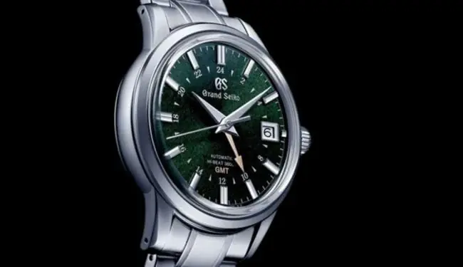 Grand Seiko watch with a green dial photographed at an angle on a black background