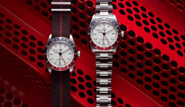 Two Tudor watches on straps against a red background