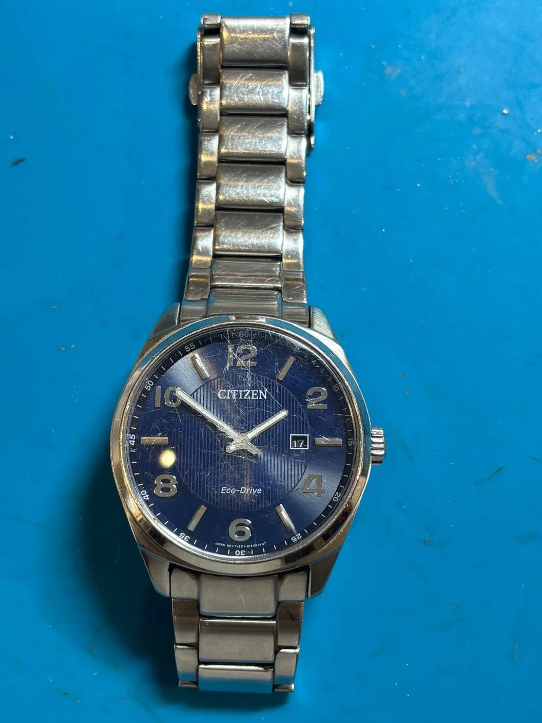 Citizen Eco-Drive E111-S094615 before repair, with scratches on the glass and bracelet